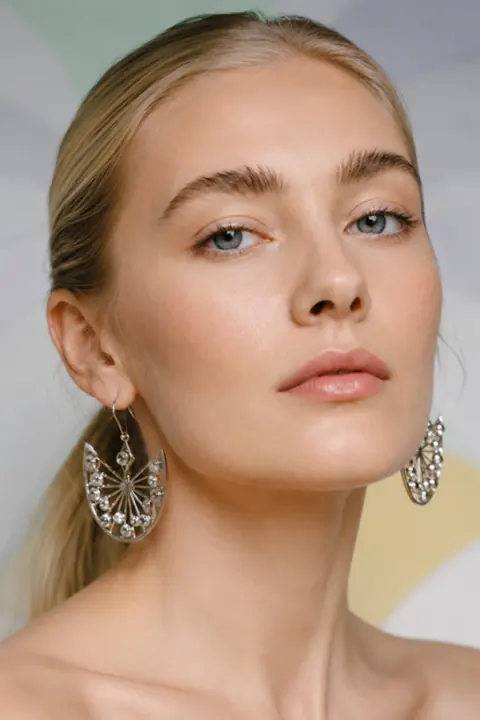 AI model wearing silver filigree earrings, close-up beauty shot