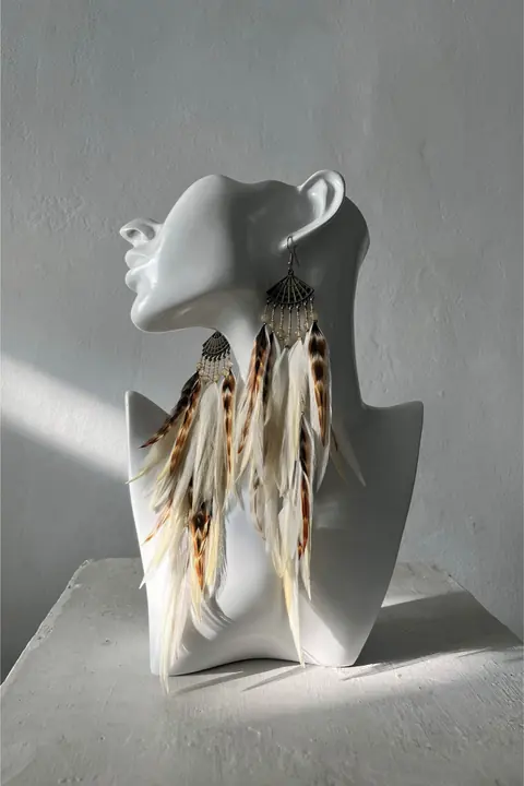 Product photo sent by the brand: feather earrings on a white mannequin bust